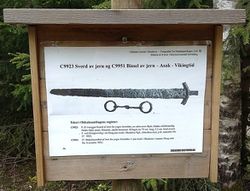 Infotavle med sverdkopi og bissel fra Vikingtid, funnet i området og registrert i Oldsakssamlingen.